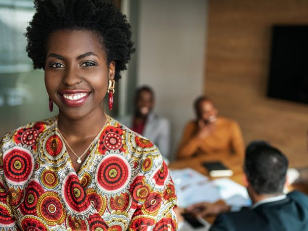 Close up of beautiful young smiling professional black african business woman coworkers hold a meeting in background