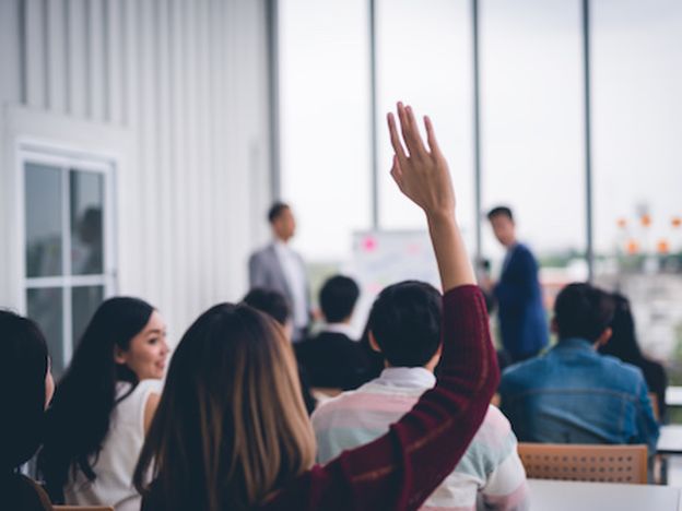 Woman raised up hands and arms in seminar class room to agree with speaker at conference seminar meeting room
