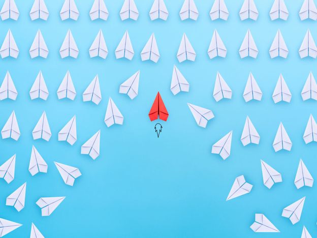 Business competition successful businessman concept with red paper plane flying overtake the other white paper planes on blue background
