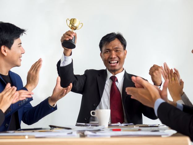 Businessman clapping hands with trophy reward winner champion and successful for business