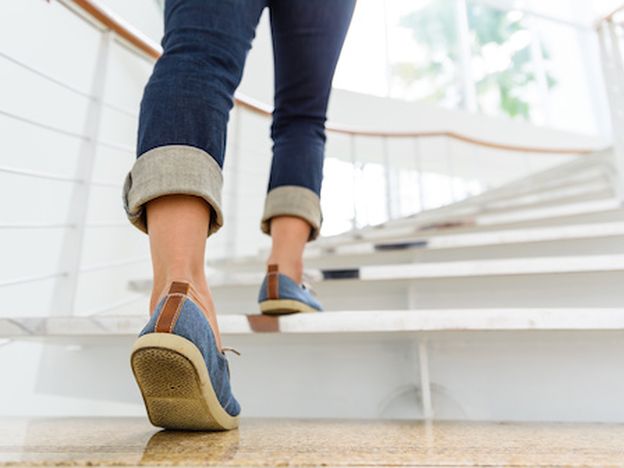 Young adult woman walking up the stairs with sun sport background