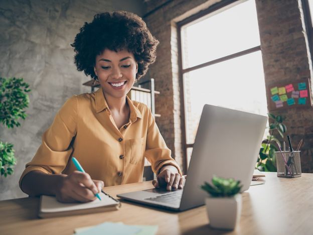 Photo of cheerful pretty cute nice girlfriend having been employed to job as executive smiling toothily sitting at desktop with laptop noting down important information