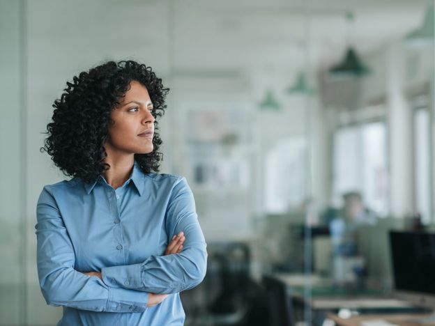 Focused young businesswoman standing alone in an office