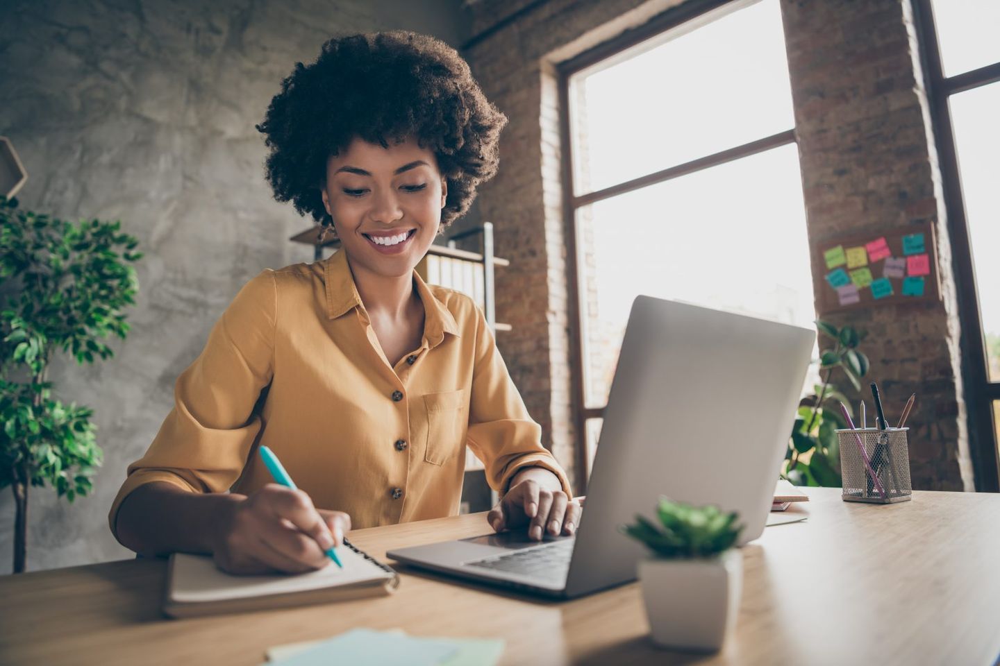 Photo of cheerful pretty cute nice girlfriend having been employed to job as executive smiling toothily sitting at desktop with laptop noting down important information