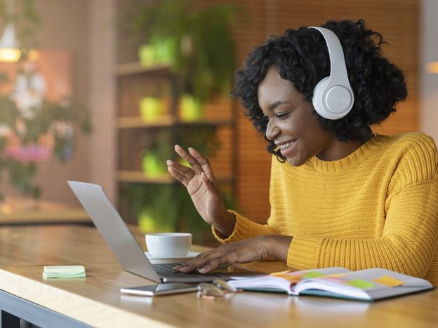 Afro girl in headset using laptop having skype conference
