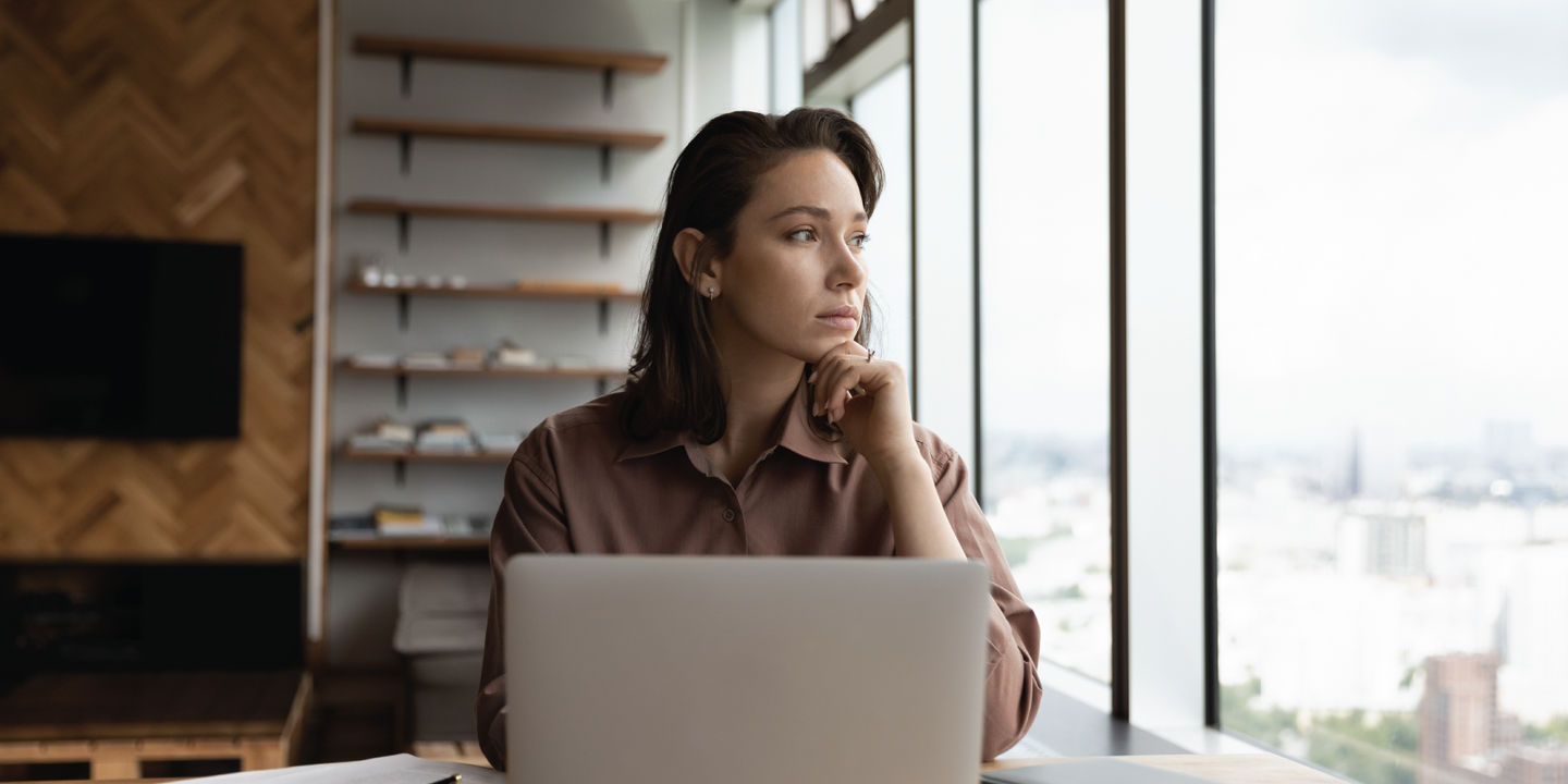 Woman on laptop looking out of window