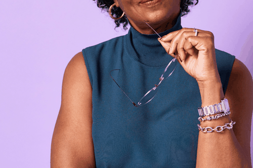 lady with a blue blouse holding reading glasses