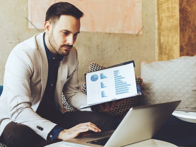 Businessman working on a laptop in a cafe and holding papers