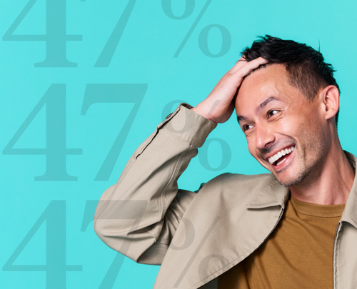 man laughing and touching hair in front of teal background