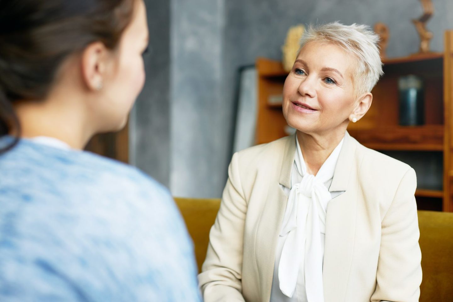 Psychology consulting and coaching concept stylish middle aged female psychologist having conversation with brunette woman client discussing problems and progress sitting in her cozy office