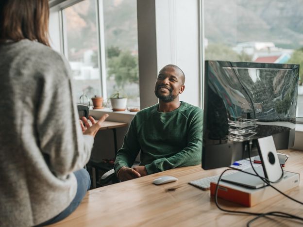Smiling african american designer talking with a colleague at work