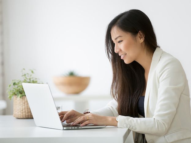 Smiling young asian businesswoman using computer working online