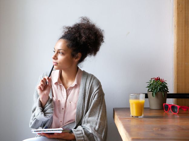 Young woman sitting at home with pen and paper