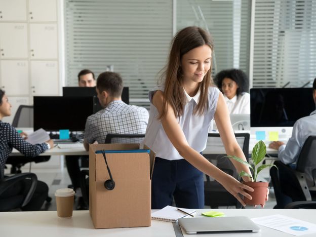 Smiling hired female company employee unpacking box with persona