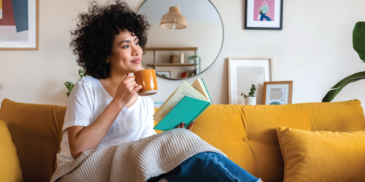 Young woman holding a cup and reading a book