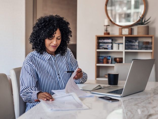 Smiling female entrepreneur going through paperwork at her dining table
