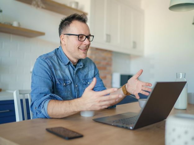 Happy adult man having a video call with a laptop at home