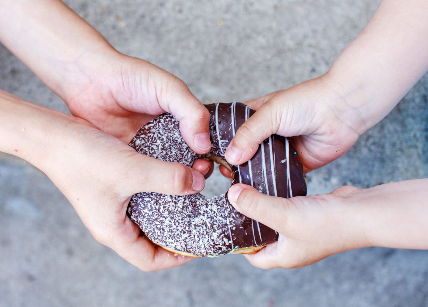 Childrens hands holding a chocolate donut two kids pull to themselves donut closeup the concept of sharing food