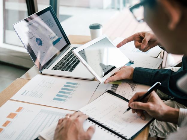 Business partnership coworkers using a tablet to analysis graph company financial budget report and cost work progress and planning for future in office room